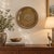 Add warmth and vintage character to your home with this decorative brass wall platter, measuring approximately 22 inches...
