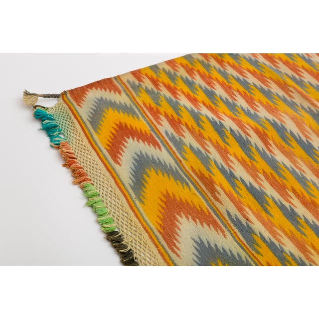 Handwoven cotton tribal Dhurrie rug with bright yellow red and blue optic pattern. Hand knotted fringe on both ends....