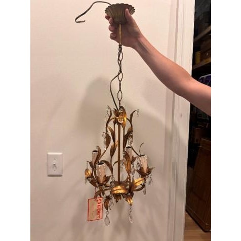 Charming Italian chandelier featuring a classic silhouette with elegant crystal accents and a warm patinated metal frame....