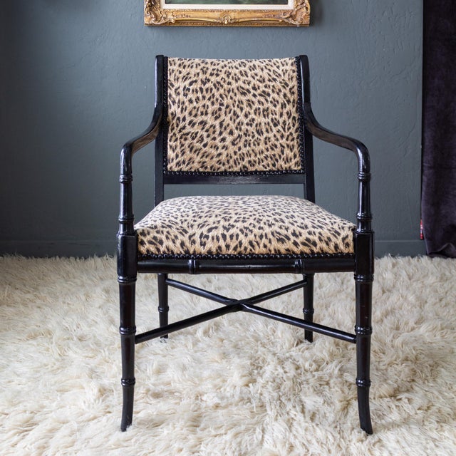 A stunning pair of French Directoire-style armchairs features faux bamboo wooden frames painted in high gloss black, with...