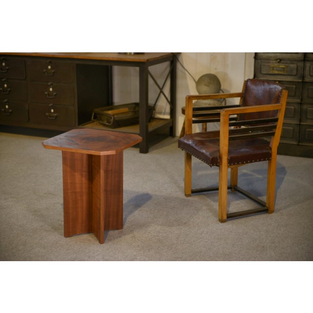 A hexagonal side table, typical of the Art Deco style, with a top featuring clean, well-defined edges. The top boasts a...