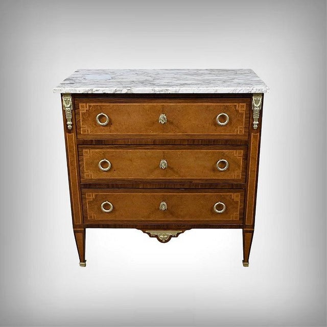 An elegant small Louis XVI-style chest of drawers, crafted in the 1940s. It features three harmoniously inlaid drawers: in...