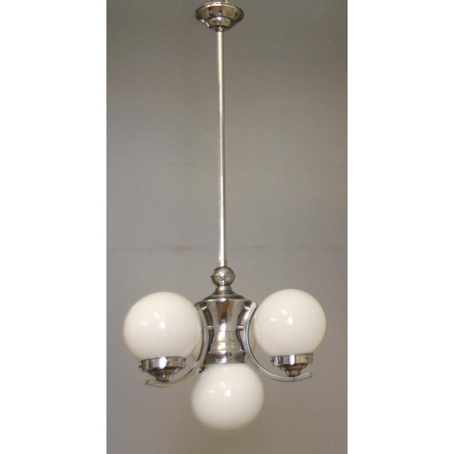 This three-arm Bauhaus chandelier consists of three white overlay glass spheres (all undamaged) and solid chrome-plated...