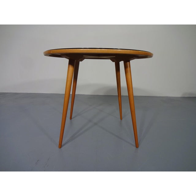 Round table with a black glass top from the 1960s. with some fine scratches on the glass top.