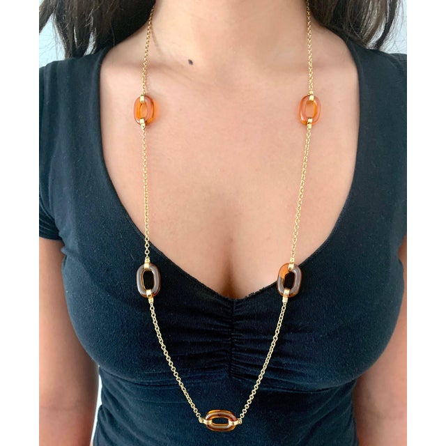 This 14k yellow gold chain necklace features 6 striking oversized oval amber glass loops. Circa 1970s - 80s, this 33” long...