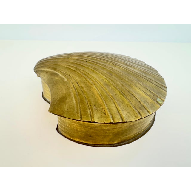 A vintage brass decorative box fashioned in the form of a sculptural scallop shell. The hinged lid is deeply molded with...