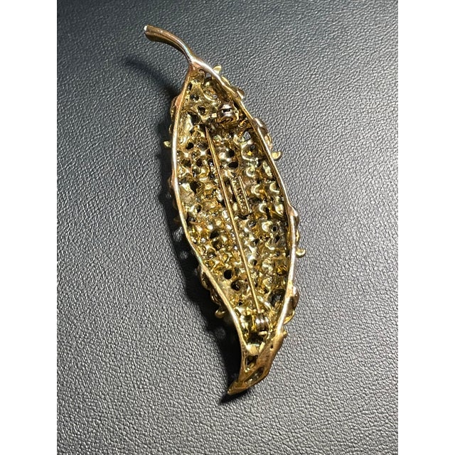Hollycraft features a pave-set array of round clear chaton rhinestones accented by textured, antiqued gold-tone leaf and...