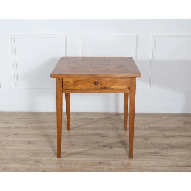 This square walnut table features a geometric inlaid top composed of bookmatched and angled walnut veneers that create a...