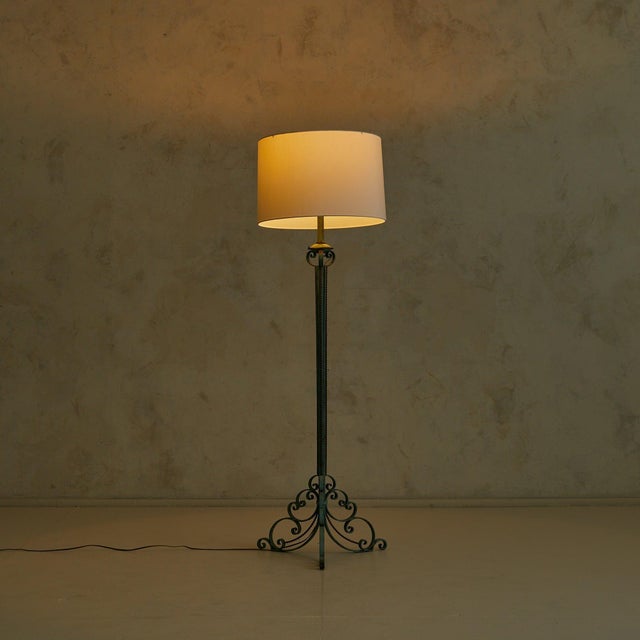 A French floor lamp from the 1940s, wrought in hand-forged iron and finished in a soft verdigris patina. The slender stem...