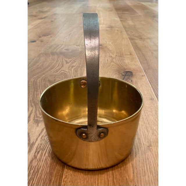 An antique English brass jelly pan with a fixed iron handle attached by hand forged copper rivets. While the pan does not...