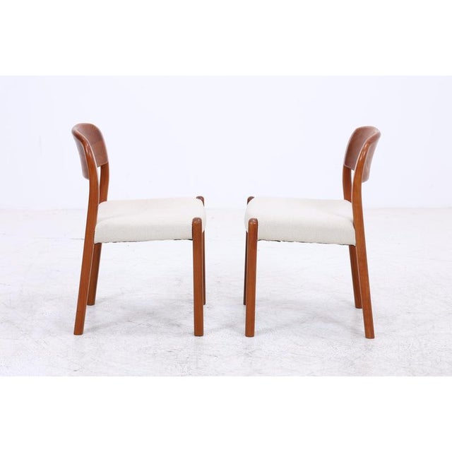 Set of two vintage Danish chairs from EMC Furniture A/S, featuring a distinctive rounded backrest and a rich teak grain....