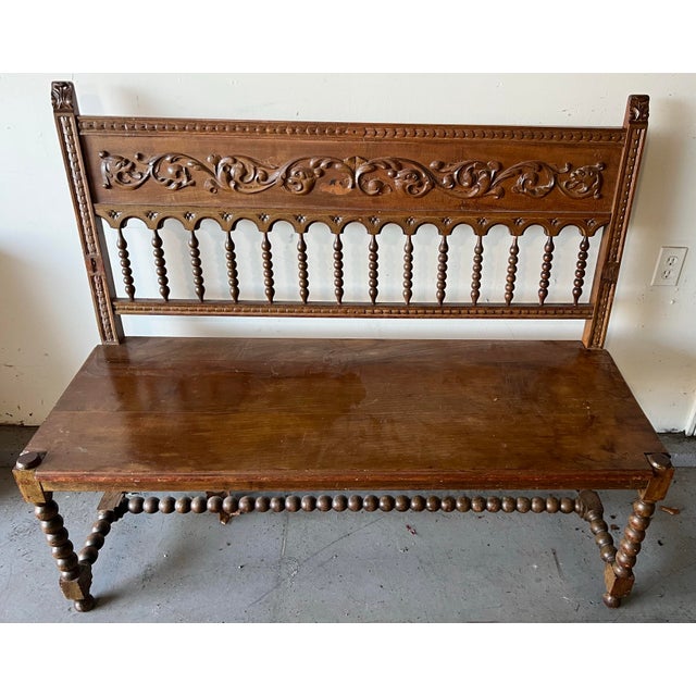 Early 20.th century Spanish hall benchcrafted in silid wood, featuring a richly carved crest rail with scrolling foliate...