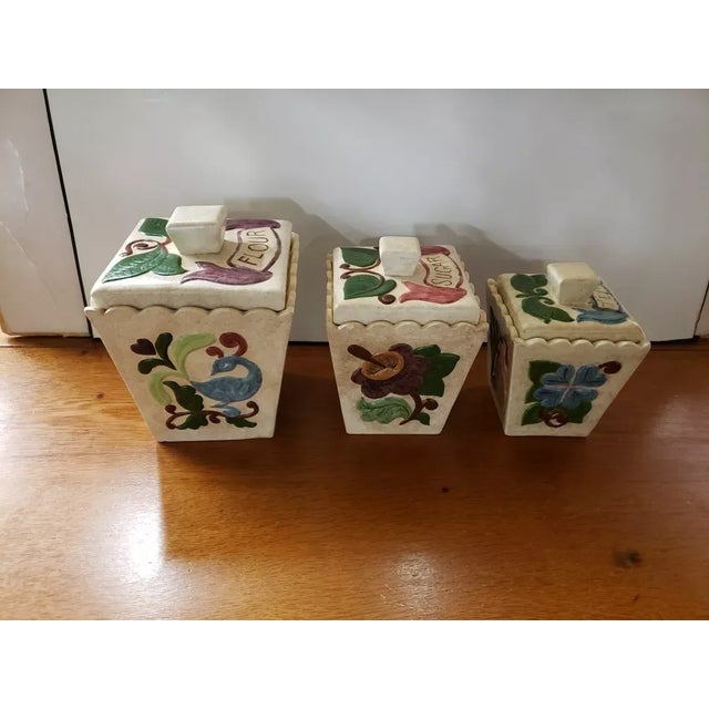 This is a 1969 Set of 3 Handmade Ceramic Canisters with Floral Motif, Flour, Sugar & Tea. They measure (from left to...