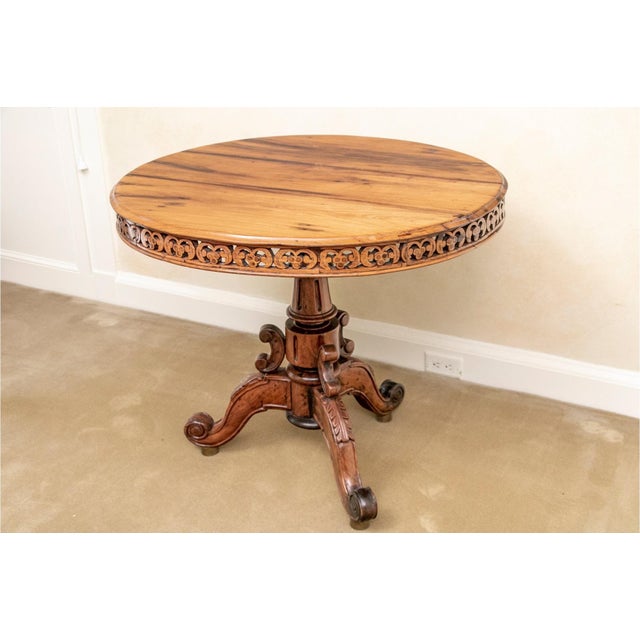 A Victorian occasional or center hall table in an exotic hardwood, with dark veining, pierced apron and an elaborately...