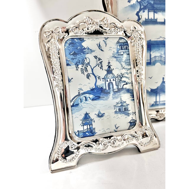 An elegant pair of vintage silverplate picture frames by Towle Silversmiths featuring delicate ribbon and garland...