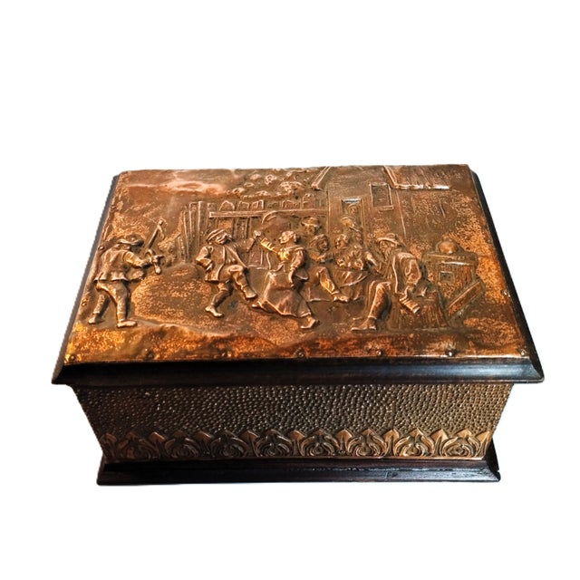 Vintage decorative box in embossed copper, featuring a lively medieval village dance scene, depicting characters in...