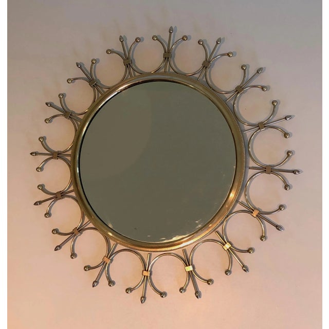 This delicate and decorative sunburst mirror is made of brass and brushed steel. This is a French work. Circa 1970.