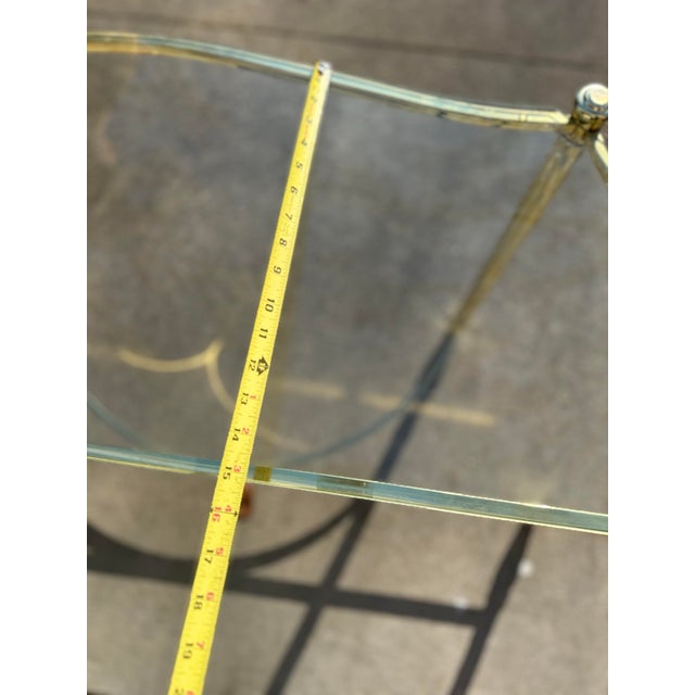 A sleek Hollywood Regency style console table showcasing a curved glass top and an elegant gold-tone frame. The light,...