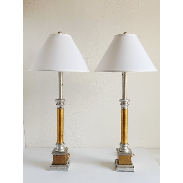 Handsome pair of two tones giltwood tall buffet lamps with a clean classic look. Featuring a slim, stepped torch like body...