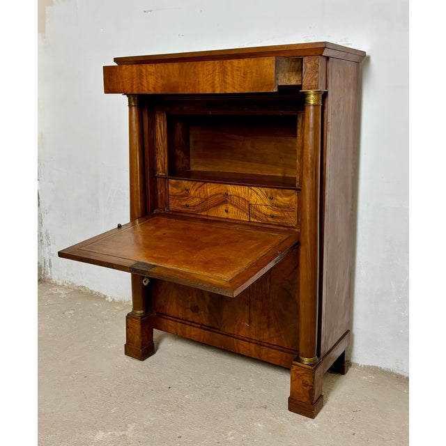 Elegant French Empire secretaire abattant crafted in walnut, featuring striking book-matched veneer, ebonized column...
