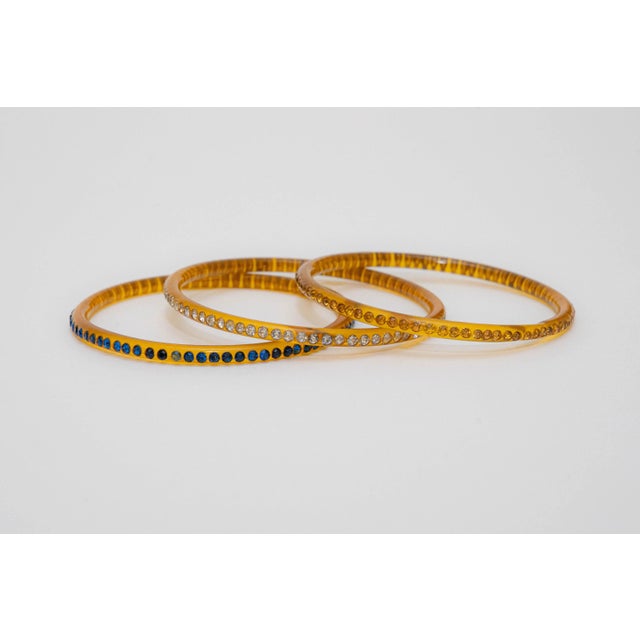 This lovely trio of vintage 1930's amber colored celluloid bangle bracelets are set with rhinestones. They are very thin...