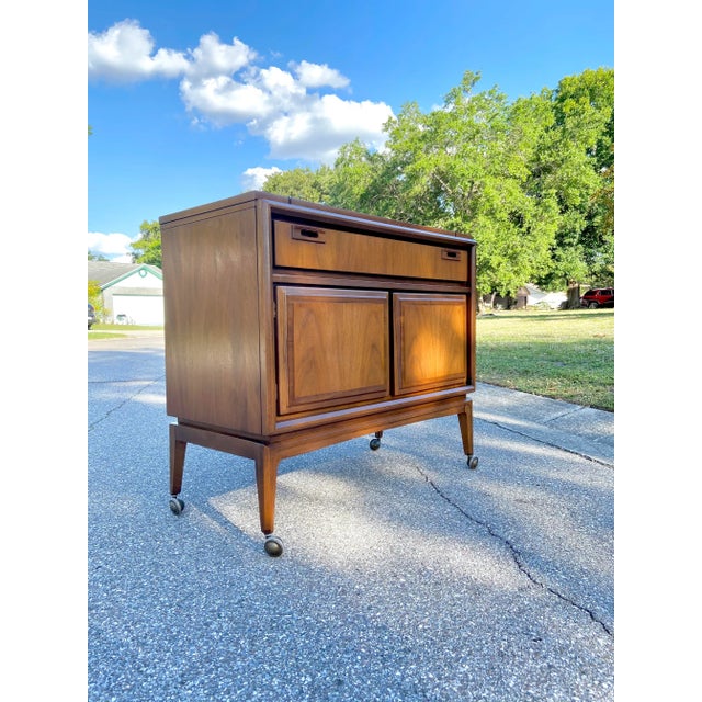 This one is awesome. Mid Century Dry Bar with Fold-Out style tabletop. Carved handles and two horizontal leafs on a piano...
