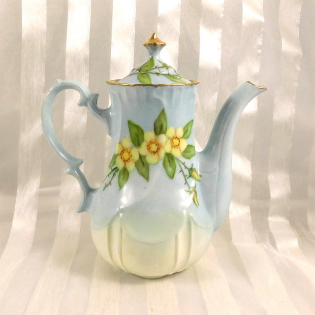 This is a small blue unmarked teapot (or chocolate pot or coffee pot) with yellow flowers and gold trim. The bvottom has a...