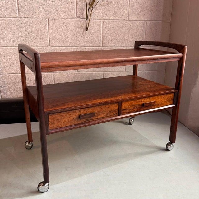 This Danish Modern rosewood trolley bar cart was manufactured by Arrebo Mobler of Denmark, circa 1960s. This stylish...