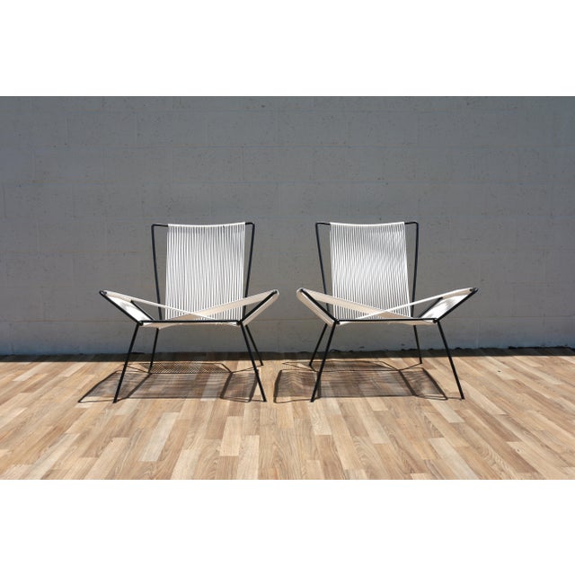 Wonderful vintage pair of sculptural iron and rope lounge chairs featuring an airy geometric silhouette with handwoven...