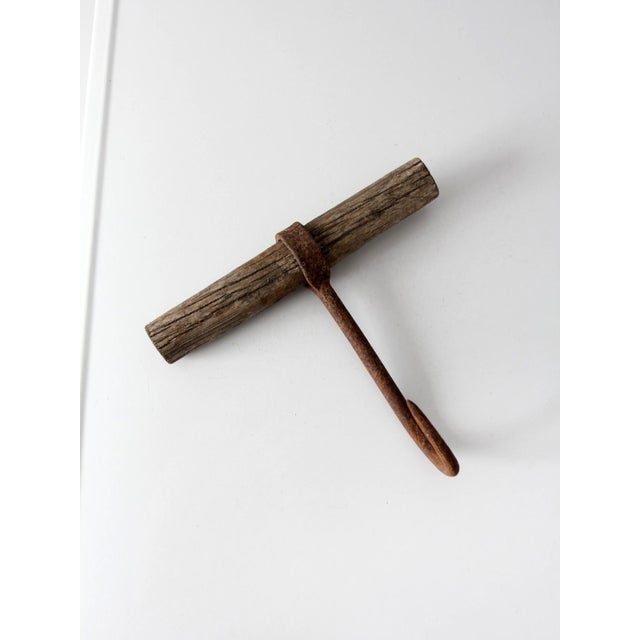This antique ice hook features a weathered wood handle paired with a beautifully aged iron surface, showcasing the honest...