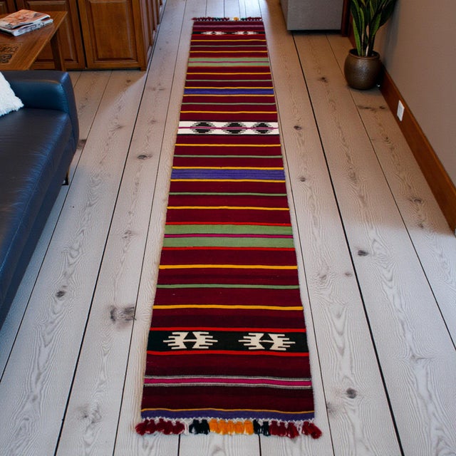 Woven in Central Anatolia (Konya region) in the 1990s, this long, narrow Turkish kilim runner brings a confident stripe...