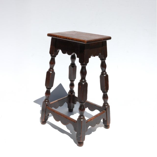 A tall late-19th-century English joint stool with a rectangular single-board seat set above shaped aprons on all four...