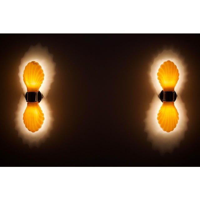 Pair of double sconces with amber pressed glass shells, lined on its interior wall with a thick layer of white opaline....
