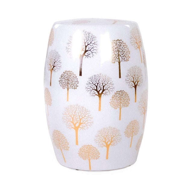 The Pauline Garden Stool is a ceramic garden stool with a classic barrel form decorated with a whimsical gold tree motif...