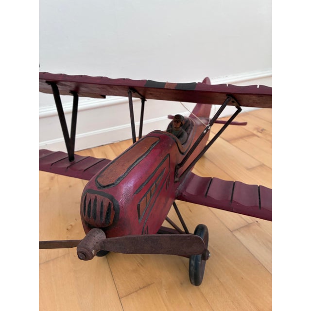 This large decorative airplane is a handmade folk art biplane model from Western Europe, dating to the 1930s. It is made...