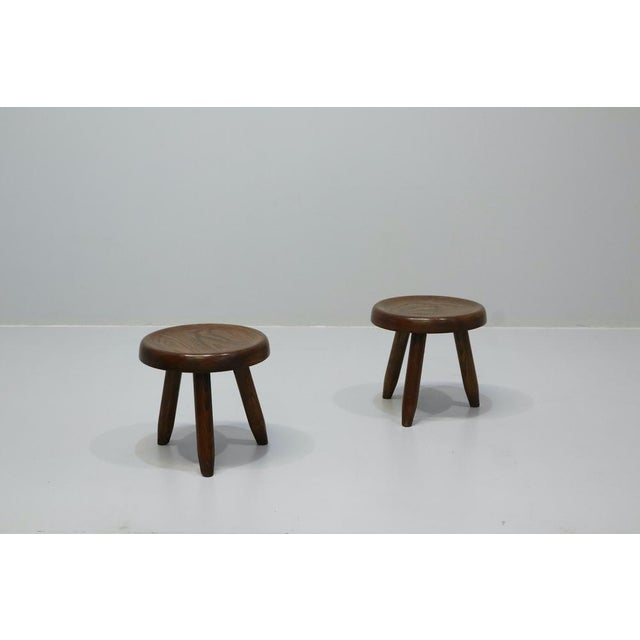 Rare mid-century French low "berger" stool in patinated cherry wood by Charlotte Perriand made in France for A. Simon in...