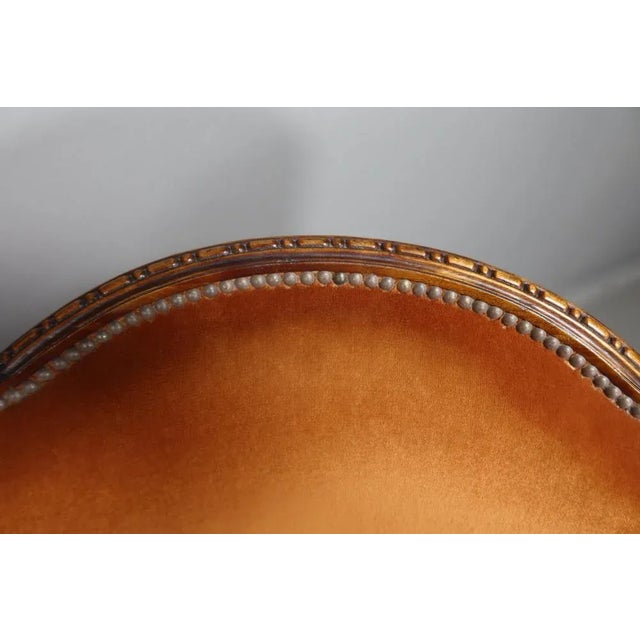 A pair of carved mahogany armchairs with scrolled backs and floral decoration. The front legs are in the shape of a...