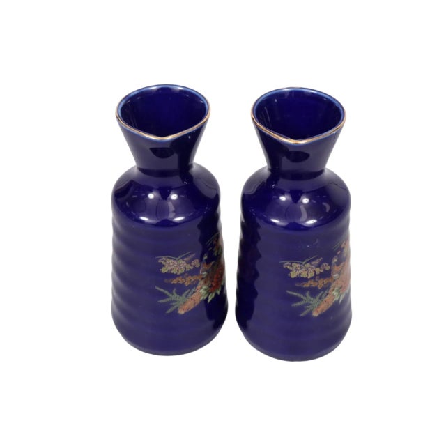 A pair of Kutani hand painted porcelain sake bottles. Cobalt blue rippled bodies are decorated in front with peacocks...
