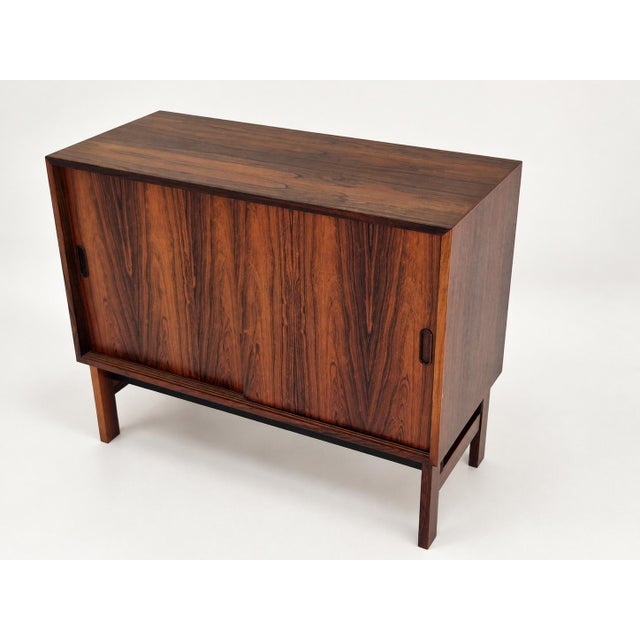 Sideboard in Santos rosewood, front with two sliding doors, behind which are shelves. Very good condition. Wall hangers on...