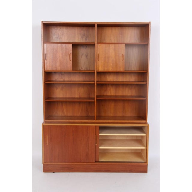 The Hundevad bookcase consists of a base cabinet with a shelf, a cutlery drawer, and a music shelf. It is enclosed by...