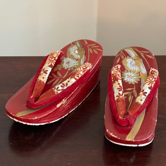 An adorable small pair of traditional Japanese wooden Geta shoes from the mid-20th century. These Geta feature a red...