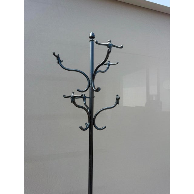 An elegant freestanding wrought iron hall stand dating to around 1900, featuring gracefully curved coat hooks, an...