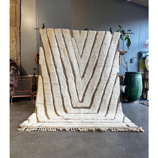 This Moroccan Beni Ouarain rug is a handwoven piece crafted from natural sheep wool, distinguished by its bold graphic...