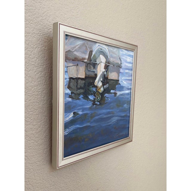 This oil painting captures the serene reflection of a boat partially submerged in shimmering blue waters, creating a...