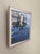 This oil painting captures the serene reflection of a boat partially submerged in shimmering blue waters, creating a...