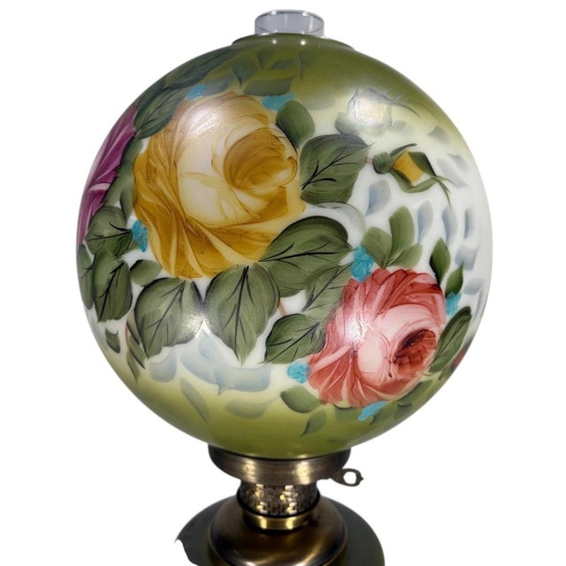 Vintage table lamp with a green and white glass body and matching spherical glass shade, both decorated with hand-painted...
