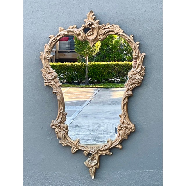 This elegant wall mirror features a classic Rococo-inspired silhouette, defined by its ornate hand-carved details and...