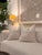 This decorative pillow features a soft ivory and cream background accented with a delicate warm beige botanical branch and...