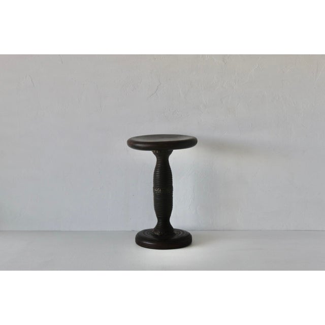 A French-style mid-century wooden pedestal stool/stand features a distinctive turned baluster column, a carved scalloped...