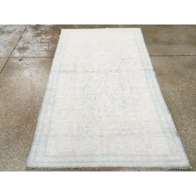 A vintage Indian Cotton Agra rug. Buff and light blue-grey tonally dominate this northern Indian scatter with an enormous...